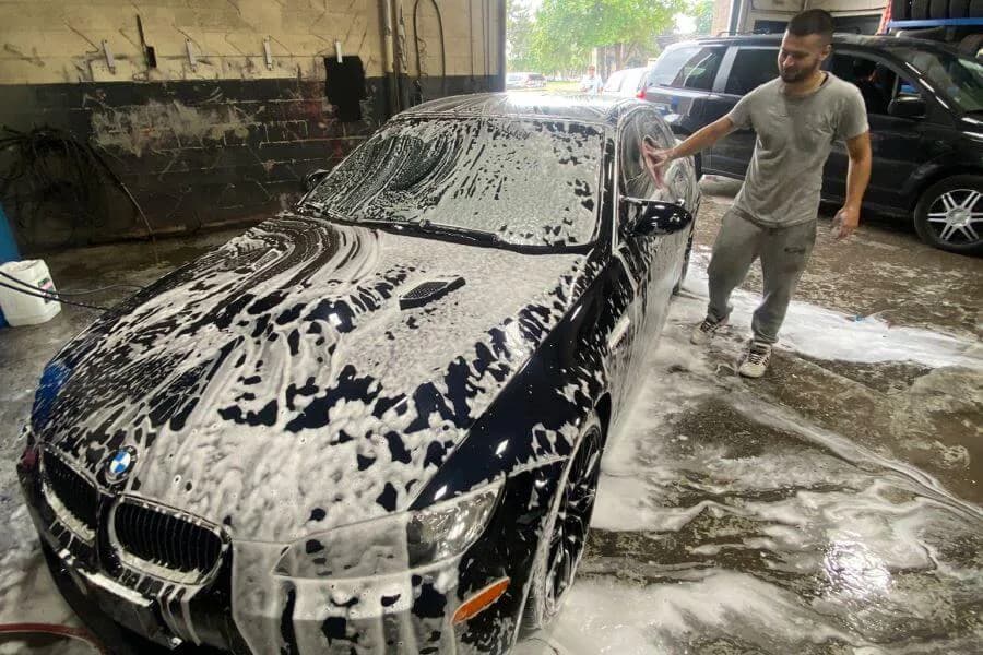 Black BMW covered in wash foam during an exterior hand wash